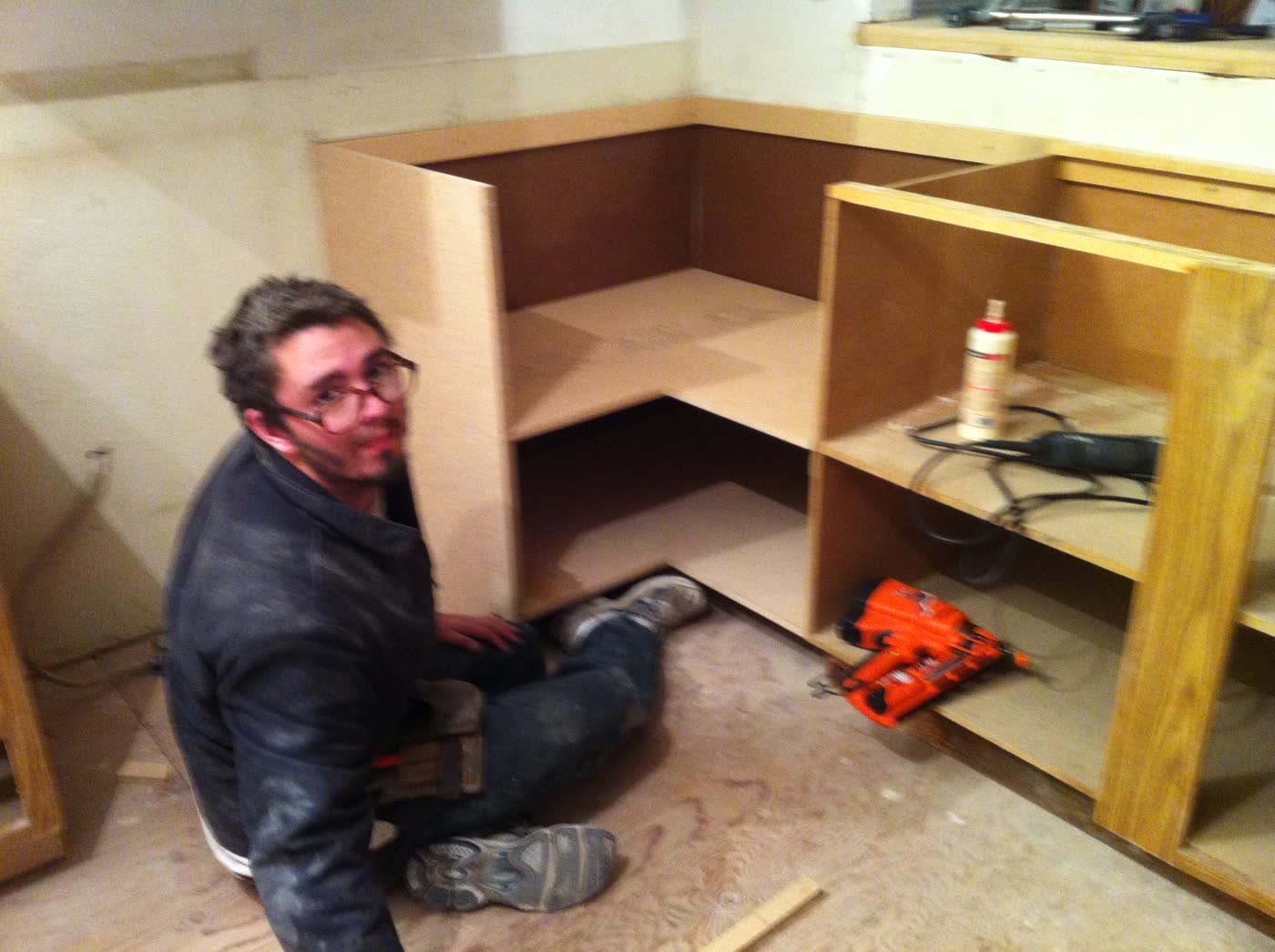 Carpenter on the floor putting plywood cabinet boxes together