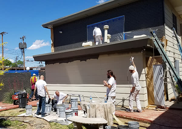 Crew painting the outside of a house on a sunny day