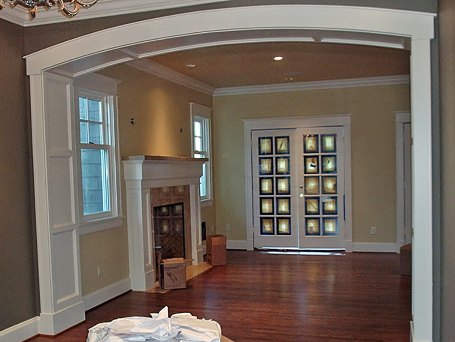 Remodeled room with an arched opening, glass doors and a fireplace