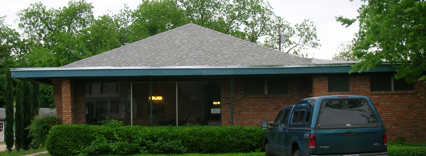 Low commercial building with green trim and a work truck out front