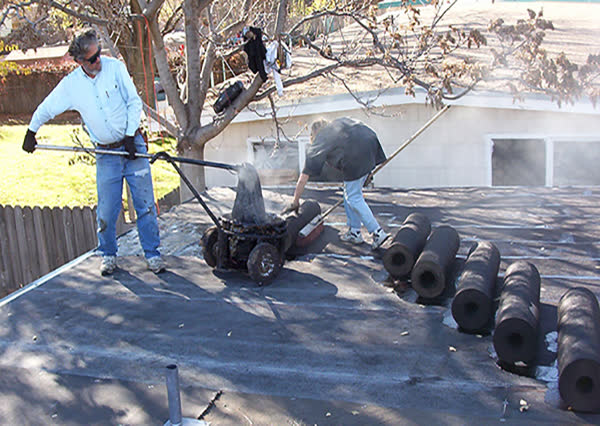 Crew rolling out new roofing on a low-slope roof